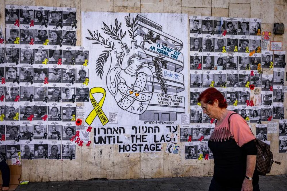 Israelis walk past a mural photographs of Israelis held hostage by Hamas terrorists in Gaza since the October 7 massacre, on Dizengoff  in Tel Aviv. The mural was designed by street artists Hastickeriot and Yiddish Feminist. March 27, 2025. Photo by Nati Shohat/Flash90 *** Local Caption *** מלחמה
חטופים
 דיזנגוף
תל אביב