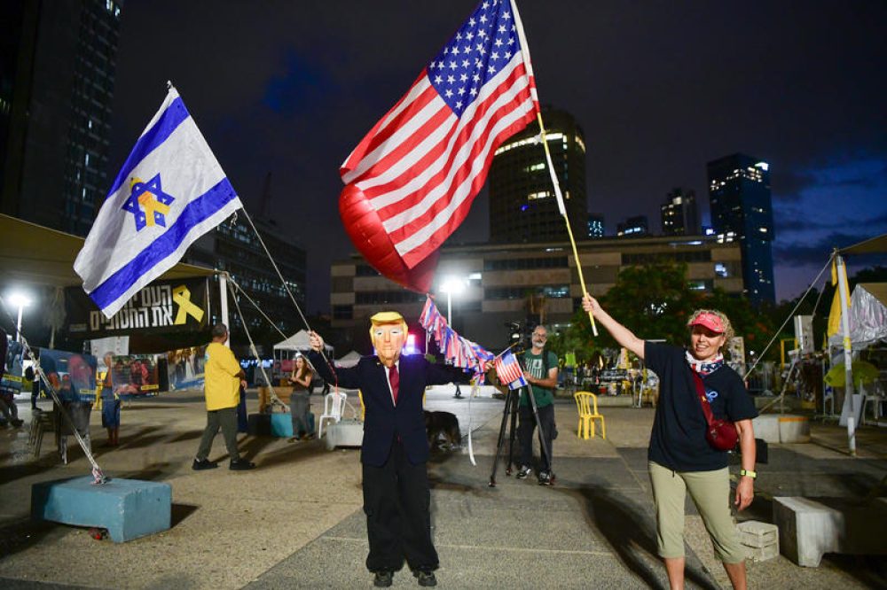Israëlische burgers met vlaggen en verkleed als Donald Trump vieren de aanstaande vrijlating van de gijzelaars in Gaza - Foto: Avshalom Sassoni/Flash90