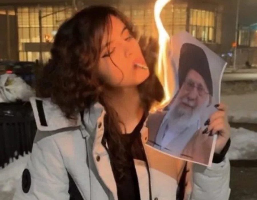Een demonstrant steekt haar sigaret aan met het brandende portret van de Iraanse dictator Ali Khamenei - X