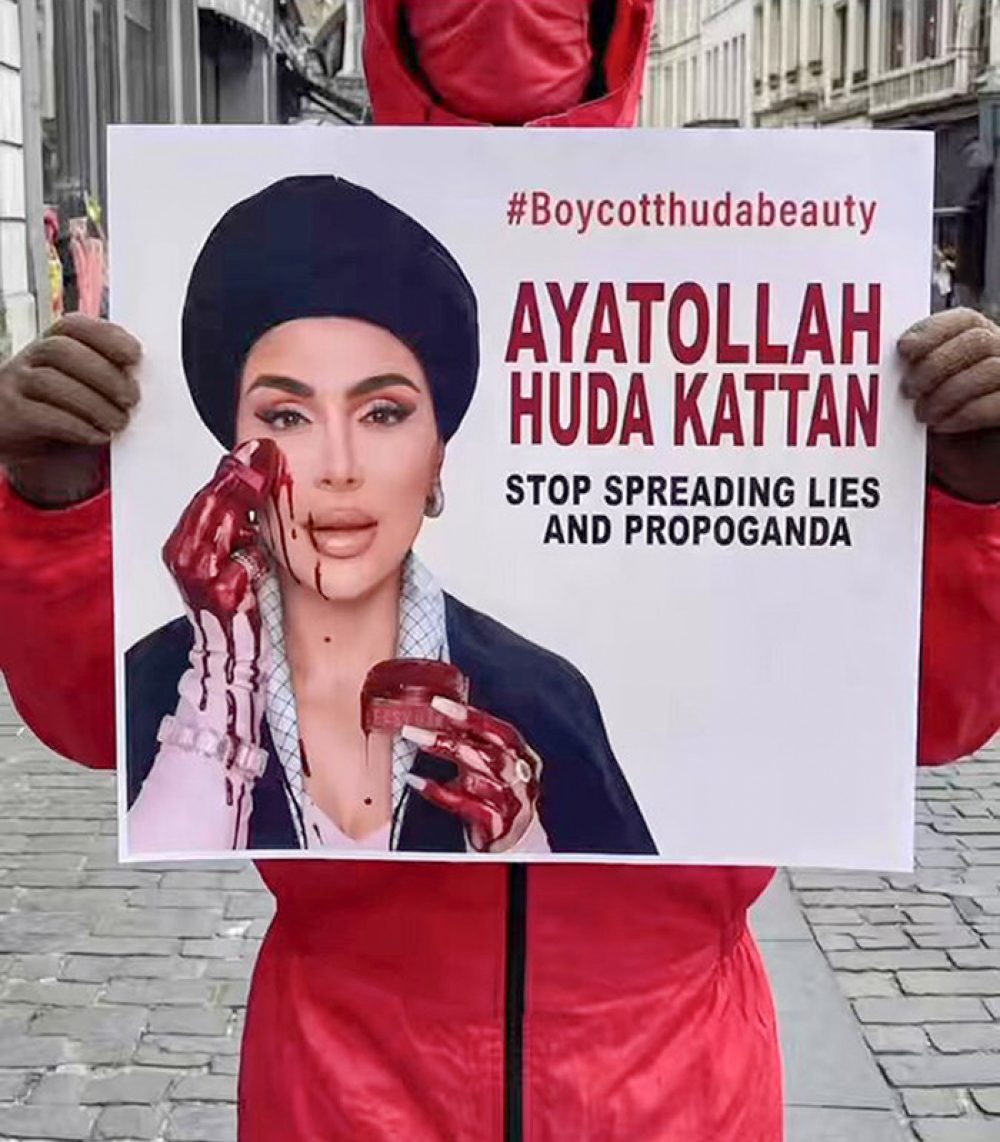 Een demonstrant toont een afbeelding van Huda Kattan 
als ayatollah die zich met bloed opmaakt