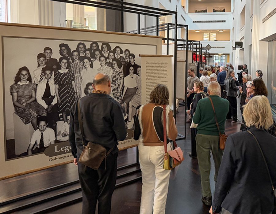 Bezoekers lopen langs de klassenfoto , het beginpunt van de expositie Lege stoelen in de klas in het Stadsarchief Amsterdam. Foto: Yoram Groen