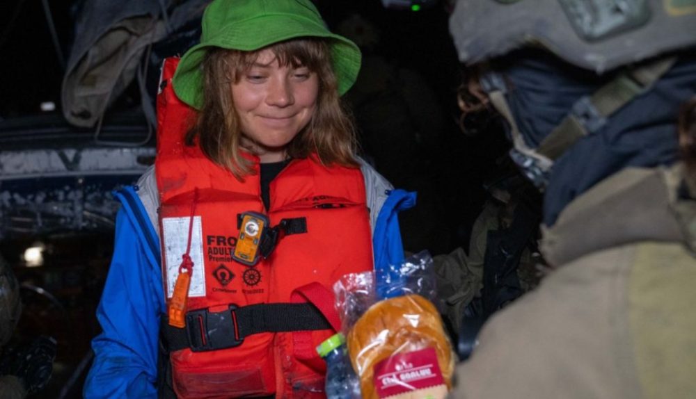 Greta Thunberg neemt een broodje aan van een Israëlische commando, aan boord van de onderschepte 'Gaza Vrijheidsvloot' in juni - Foto: IDF